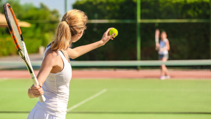 Young woman playing tennis on court tenis - reklama